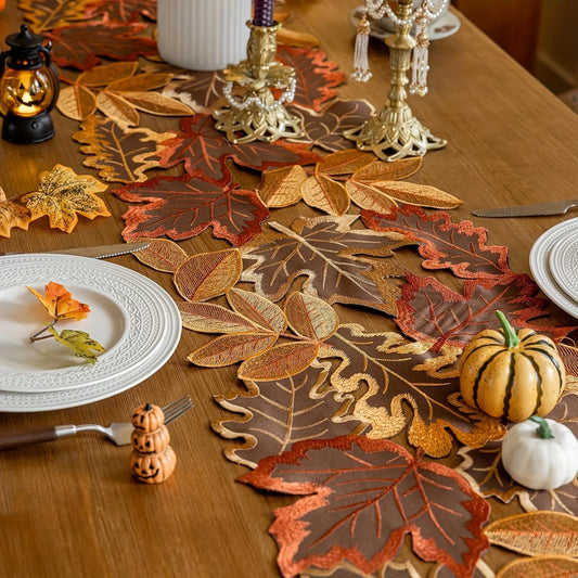 Decorative table setting with leaf-patterned placemats and small pumpkins on a wooden table.