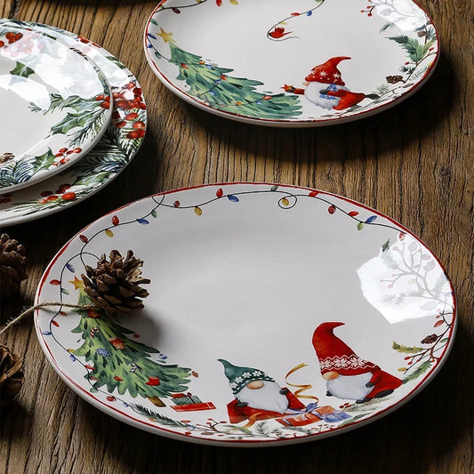 Set of Christmas-themed ceramic plates with gnomes and trees on a wooden surface.