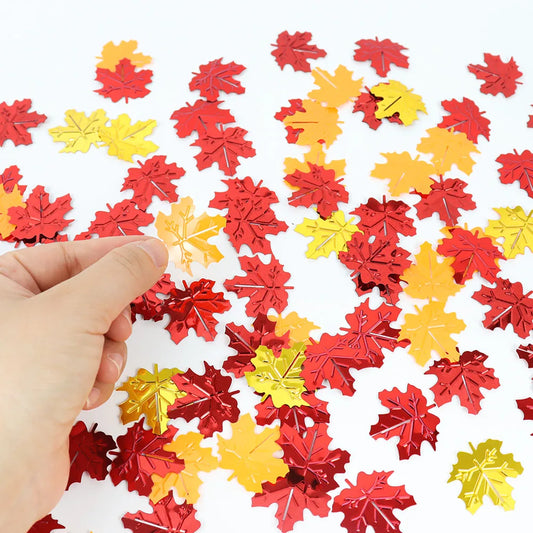 Red and yellow leaf-shaped confetti on a white background with a hand holding a leaf.