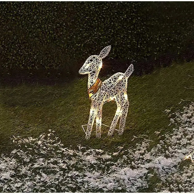 Decorative LED deer figure on a grassy area with snow, glowing warmly.