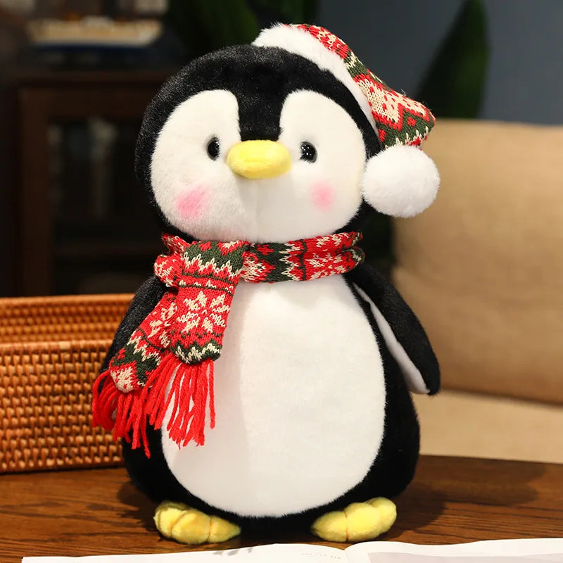 Plush penguin toy wearing a red scarf and hat on a wooden surface.