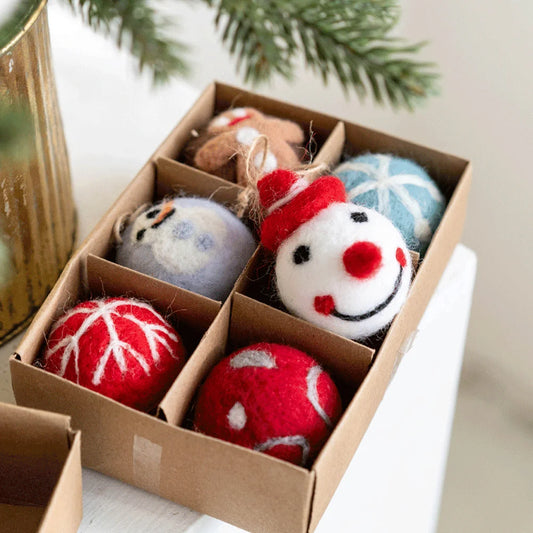 Box of felted wool ornaments with a snowman design, including red, white, and blue colors, on a light background.