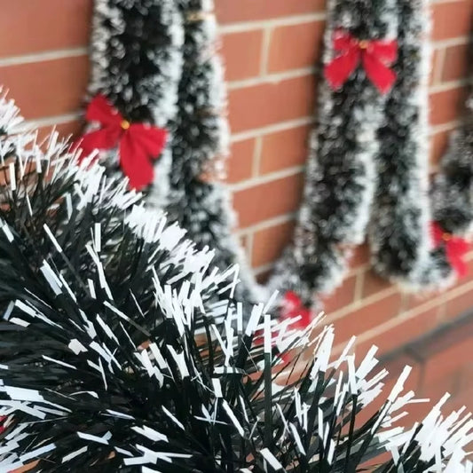 Decorative tinsel with red bows against a brick wall