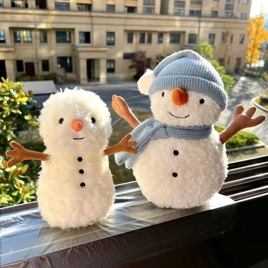 Two plush snowmen on a window sill with a cityscape in the background