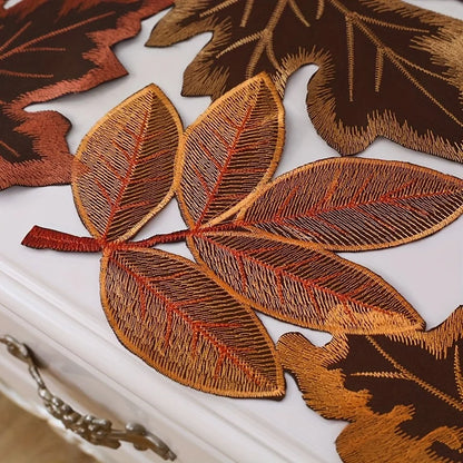 Embroidered leaf patches in brown and orange on a white surface.