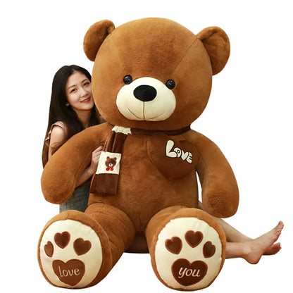 Large brown teddy bear with 'love' and heart designs, held by a person on a white background