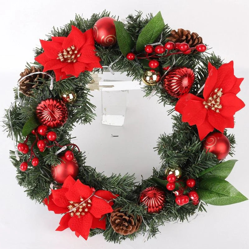 Decorative Christmas wreath with red flowers, berries, and pinecones on a white background