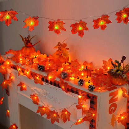 Decorative string lights shaped like leaves and pumpkins on a mantel with a white background.
