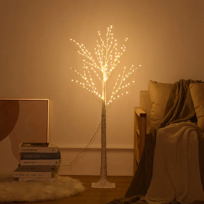 Decorative light tree in a room with books and a sofa.