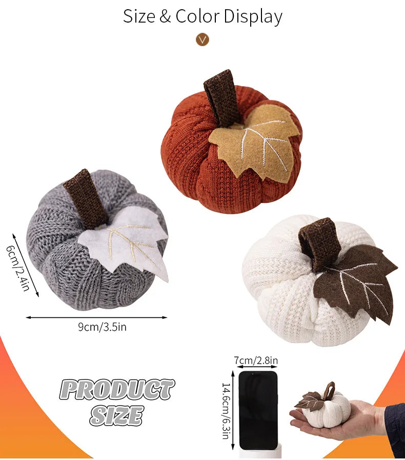 Three knitted pumpkins in different colors with leaf decorations, shown with measurements and a smartphone for scale.