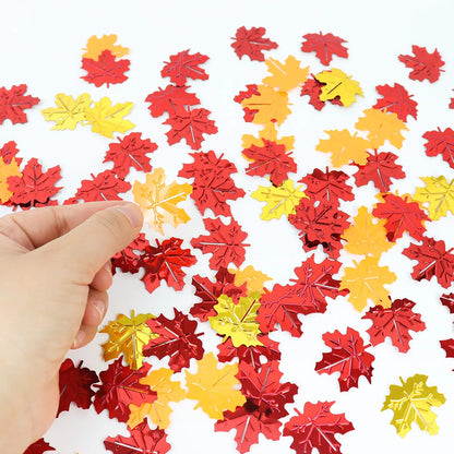 Red and yellow leaf-shaped confetti on a white background with a hand holding a leaf.