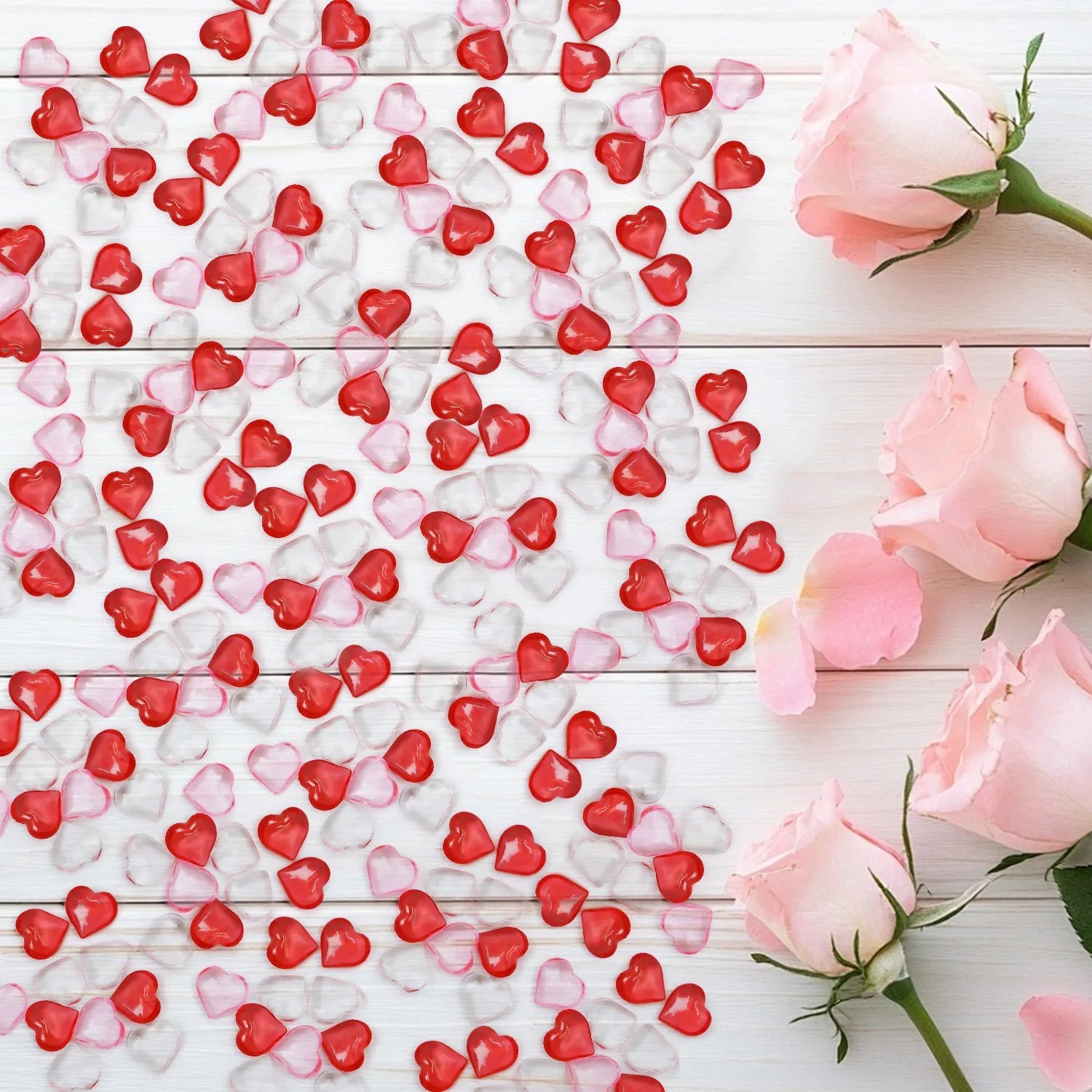 Red, pink, and white heart-shaped candies on a wooden surface with pink roses.