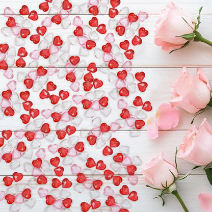 Red, pink, and white heart-shaped candies on a wooden surface with pink roses.