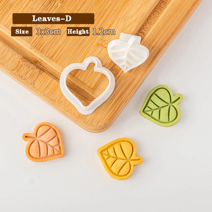 Leaf-shaped cookie cutters on a wooden board with measurements displayed.