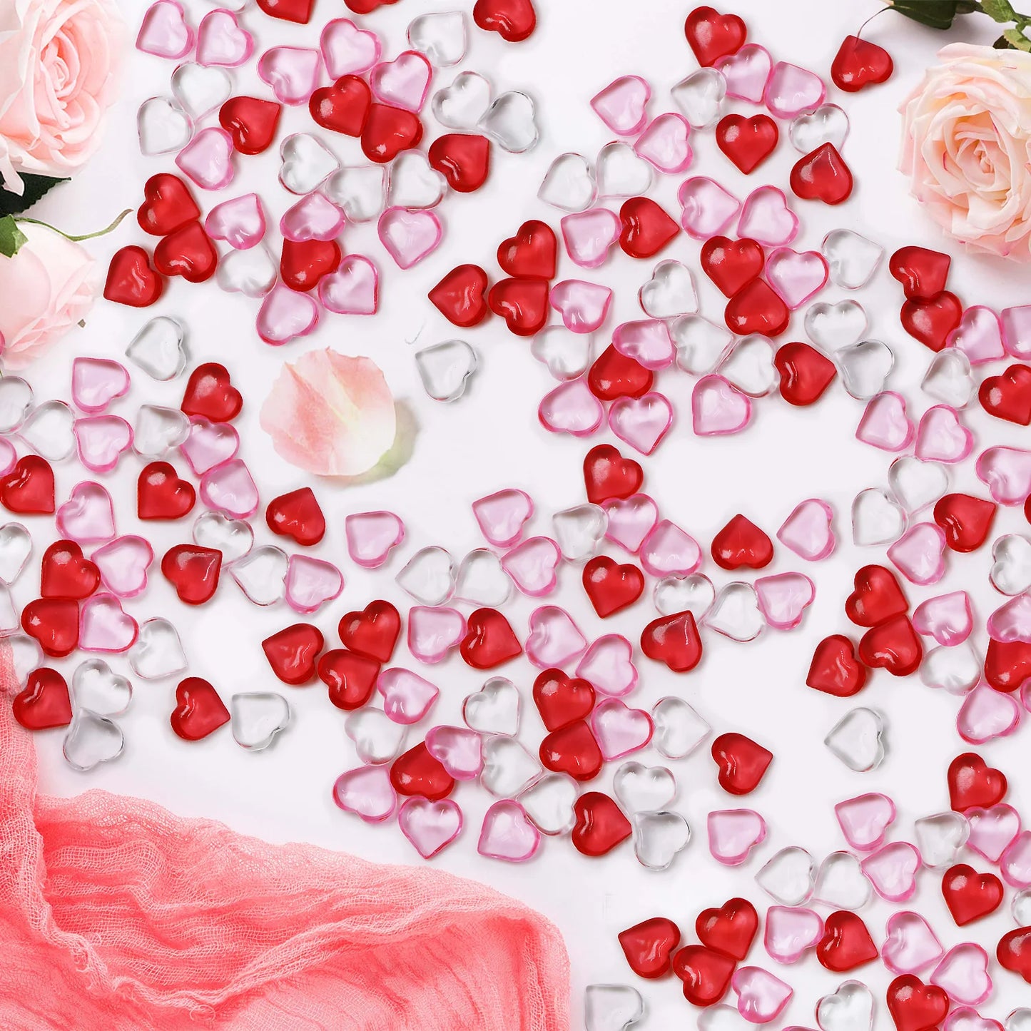 Heart-shaped confetti in red, pink, and clear colors on a white background with roses.