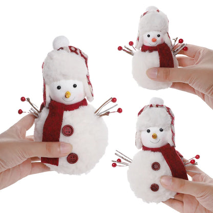 Three small snowman toys with red scarves and hats held by hands on a white background