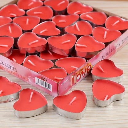 Heart-shaped red candles with a box labeled 'Romantic Love' on a wooden surface.