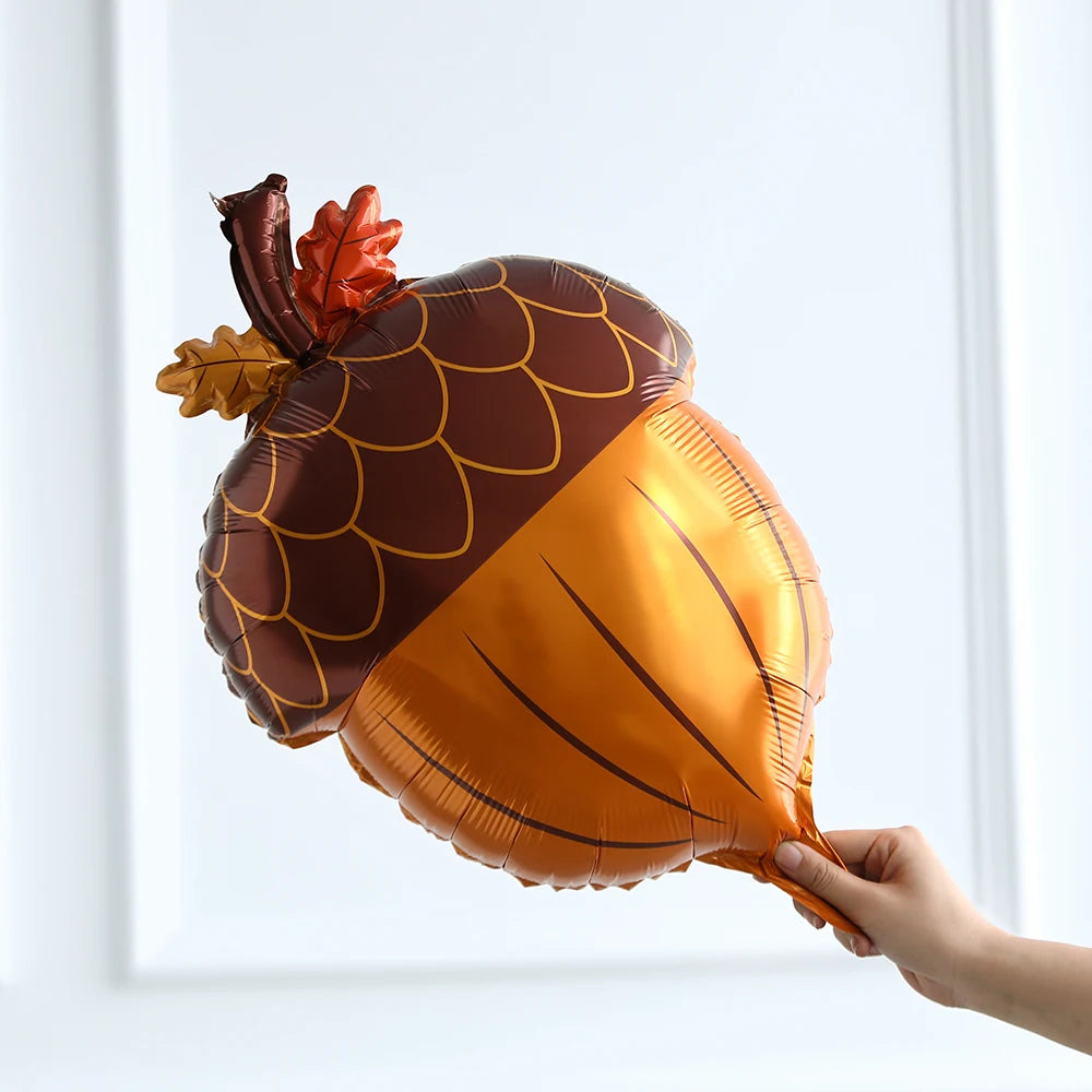Hand holding a large acorn-shaped balloon against a white background