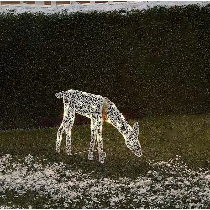 Decorative LED deer figure on grass with a hedge background