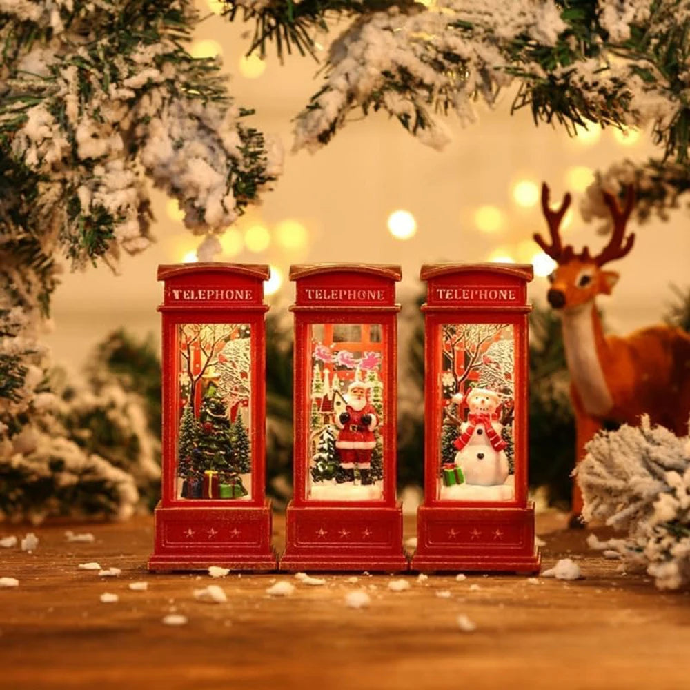 Three red telephone booths with Christmas scenes inside, surrounded by festive decorations including a reindeer and snow-covered trees.