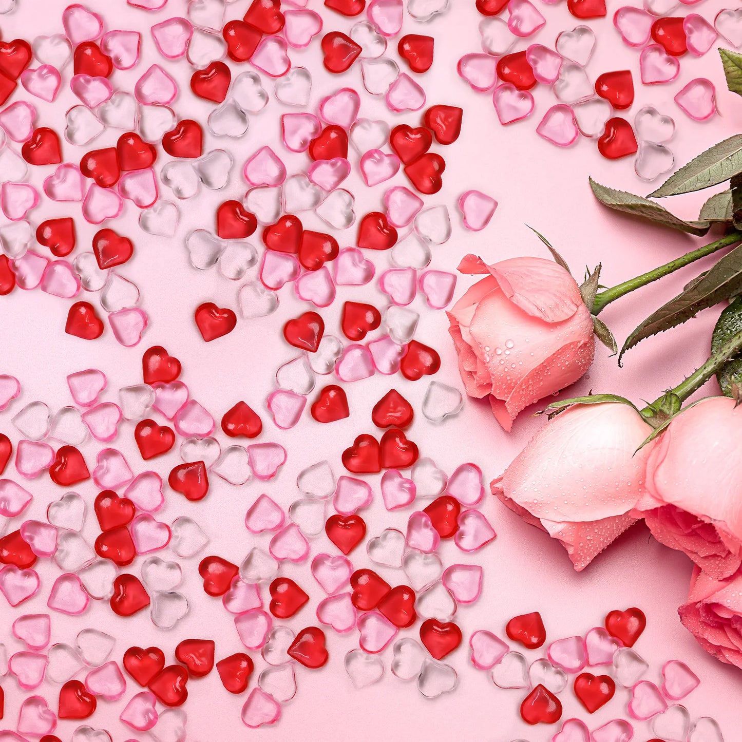 Pink and red heart-shaped candies with pink roses on a pink background