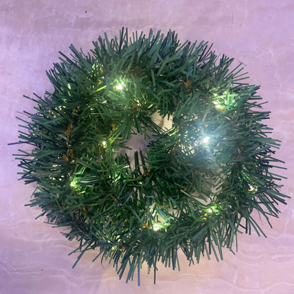 Green Christmas wreath with lights on a light pink background