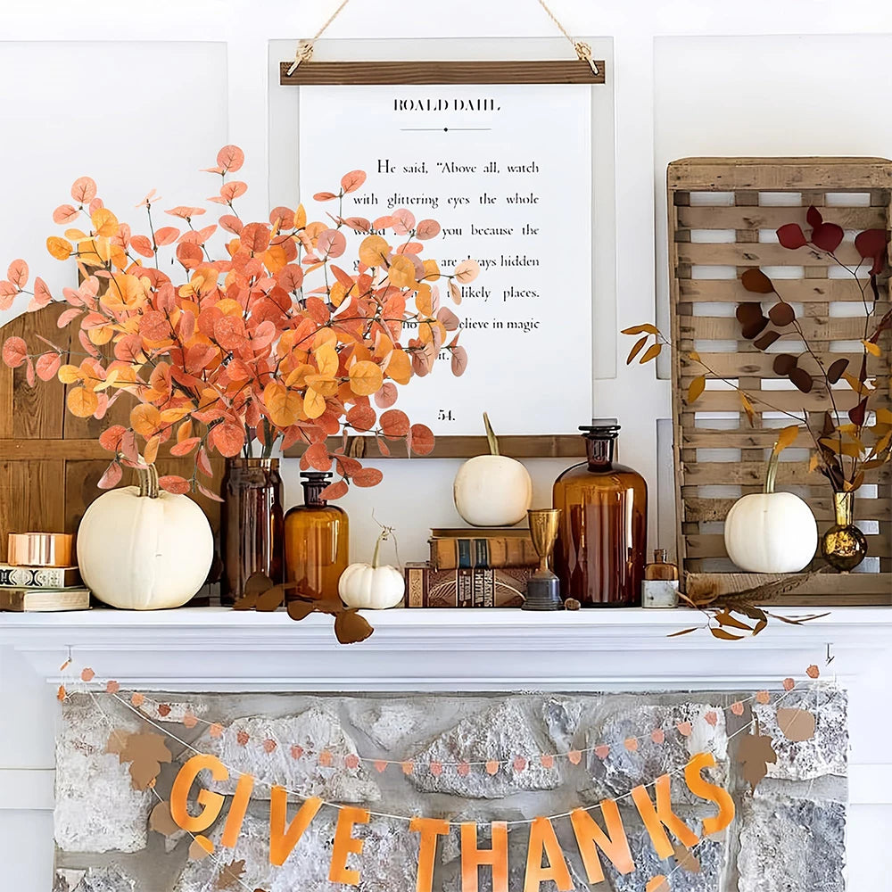 Decorative autumn mantel with pumpkins, leaves, and 'Give Thanks' banner.