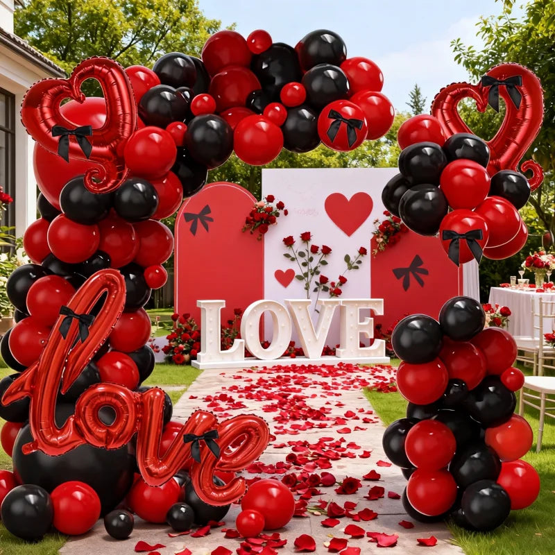 Valentine's Day-themed balloon arch with red, black, and heart-shaped balloons, 'LOVE' letters, and a decorated pathway.