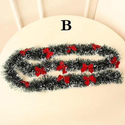 Black tinsel garland with red bows on a white surface