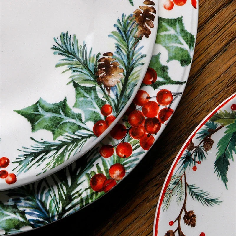 Set of Christmas-themed plates with holly and berries on a wooden surface