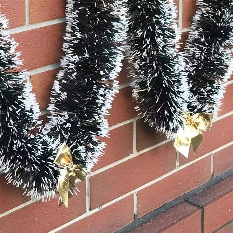 Black tinsel garlands with gold bows against a red brick wall