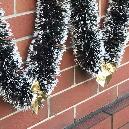 Black tinsel garlands with gold bows against a red brick wall