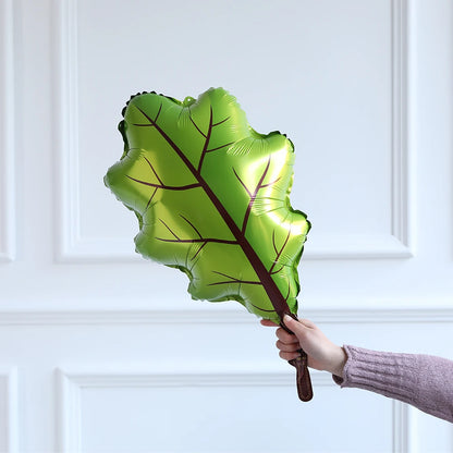Hand holding a green leaf-shaped balloon against a white paneled background