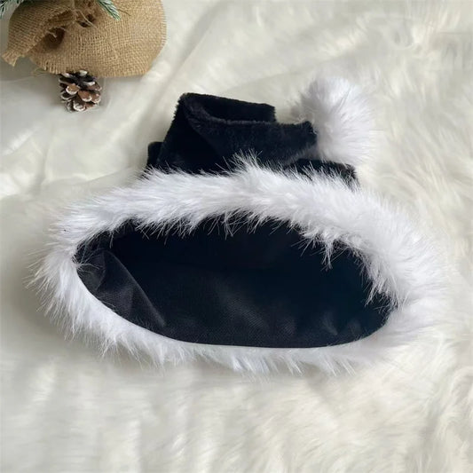 Black fur-lined slippers on a white fluffy surface with a small woven bag and pine cones in the background.