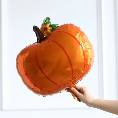 Pumpkin-shaped balloon held by a hand against a white background
