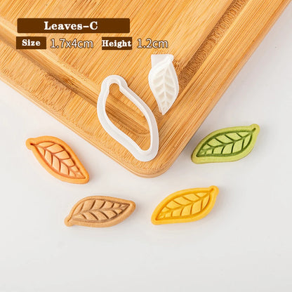 Leaf-shaped cookie cutters on a wooden board with measurements displayed.
