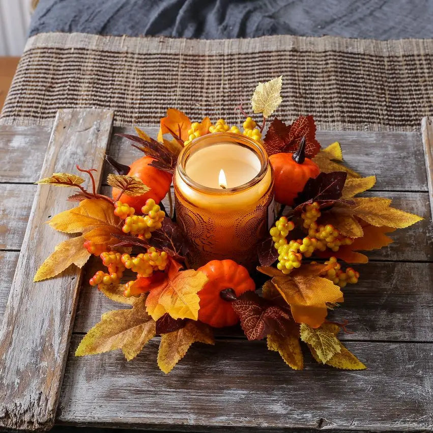 Decorative candle with fall-themed arrangement on a wooden surface