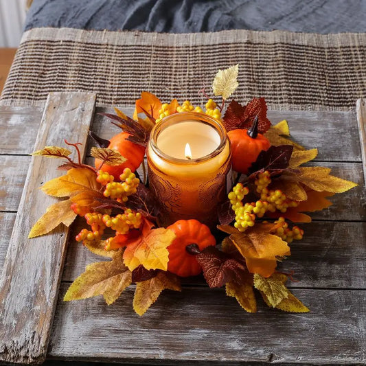 Decorative candle with fall-themed arrangement on a wooden surface