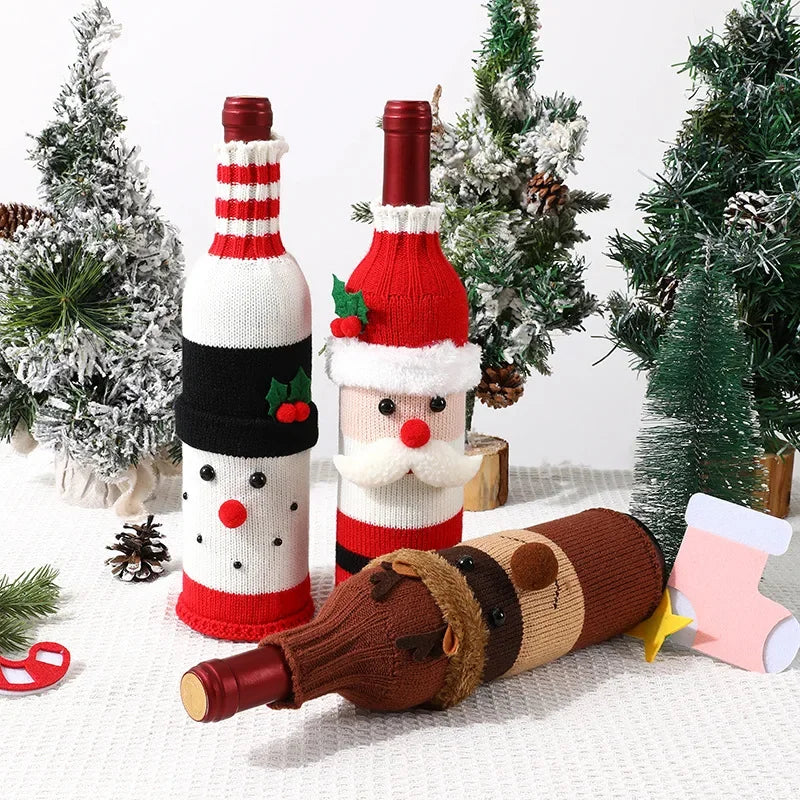Three wine bottles wrapped in festive sock designs, including a Santa Claus, snowman, and reindeer, with Christmas trees in the background.