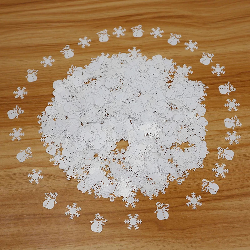 White snowflake and snowman confetti on a wooden surface