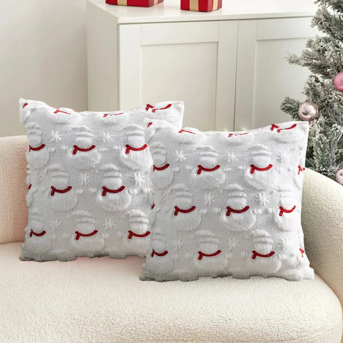 Two decorative pillows with red and white patterns on a beige couch.