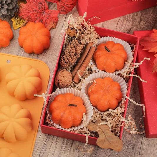 Pumpkin-shaped candles in a box with a silicone mold on a wooden surface.