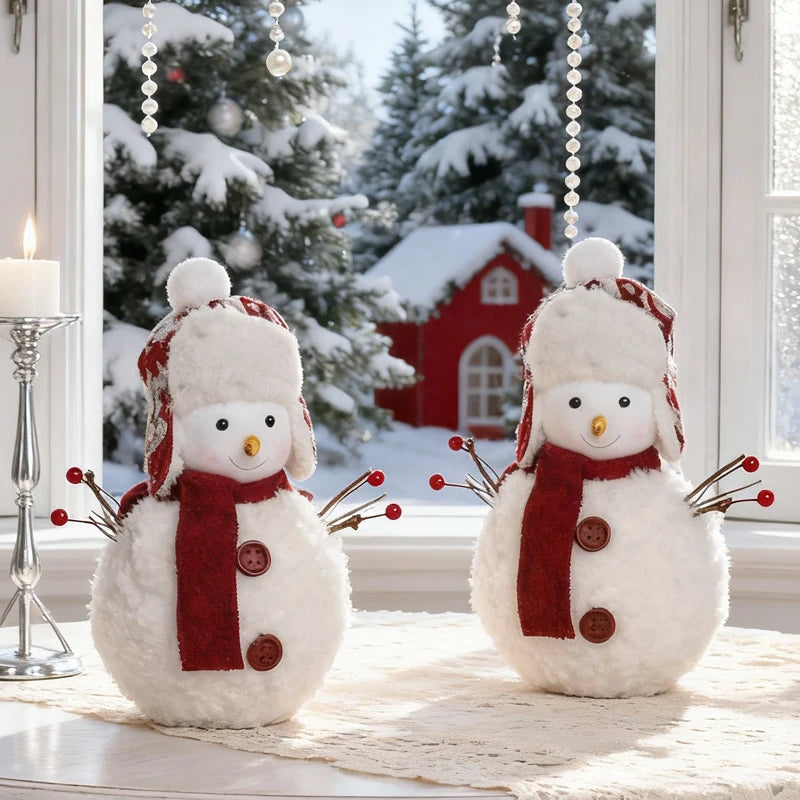Two snowman decorations with scarves and hats in front of a snowy window scene.