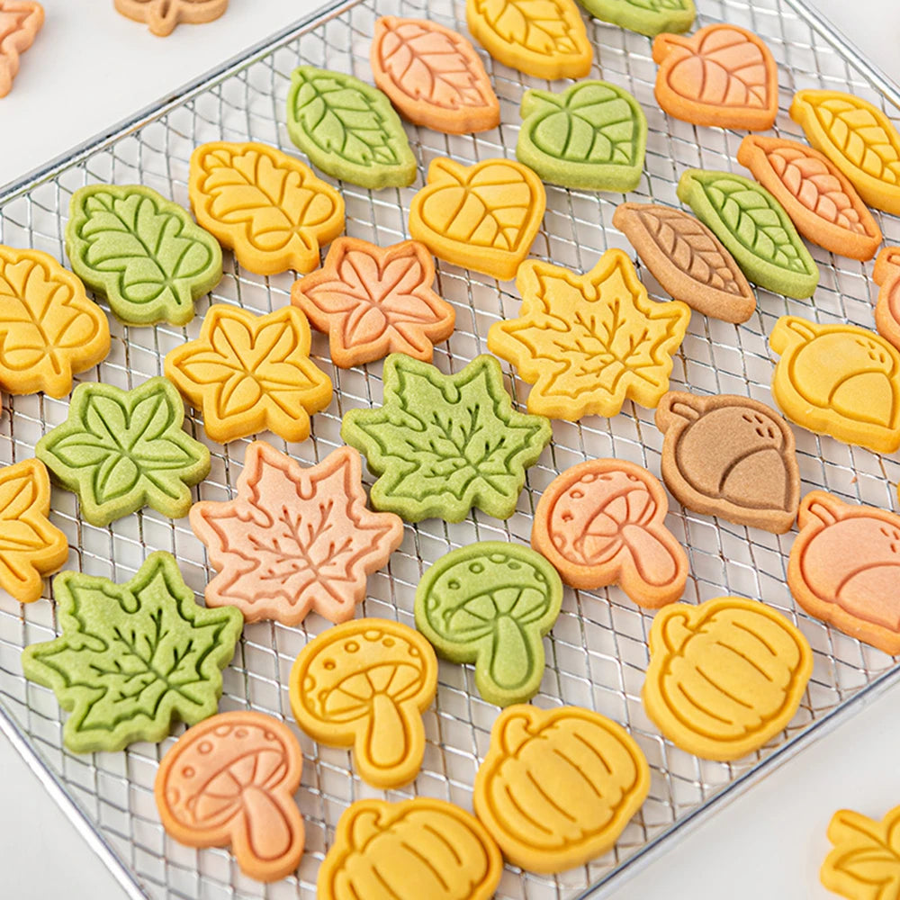 Colorful leaf, mushroom, and pumpkin-shaped cookies on a cooling rack.