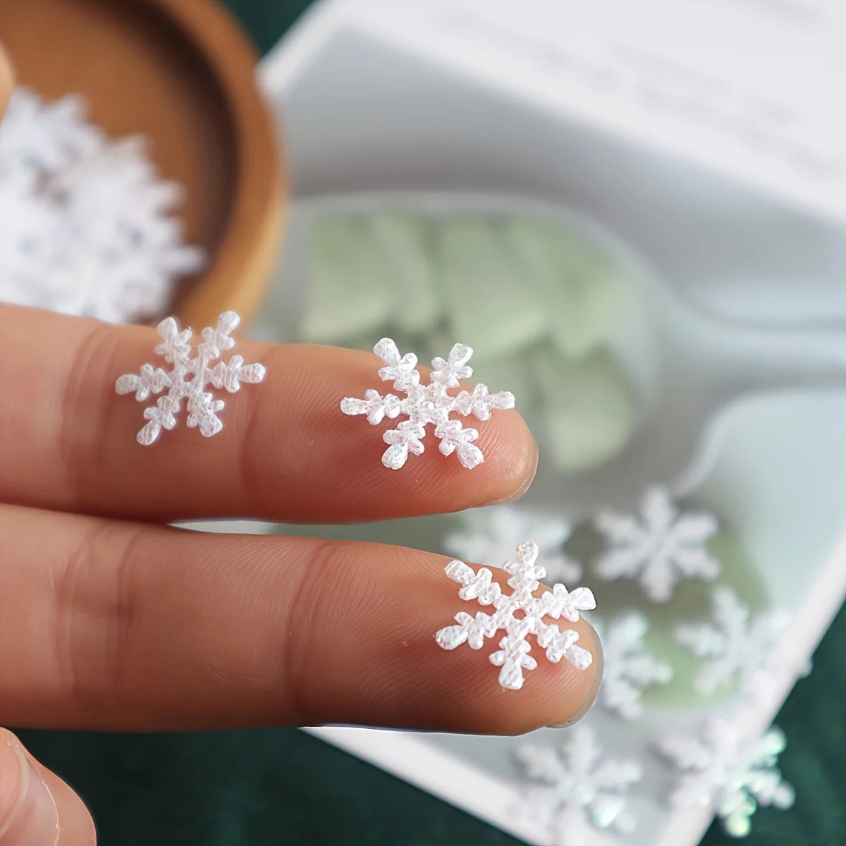 Snowflake-shaped earrings held between fingers with a blurred background