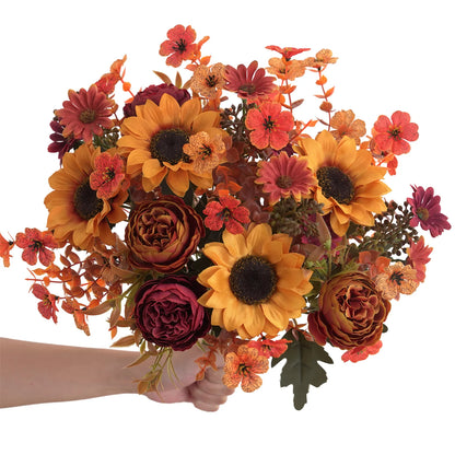 Bouquet of autumn flowers including sunflowers and roses held by a hand on a white background