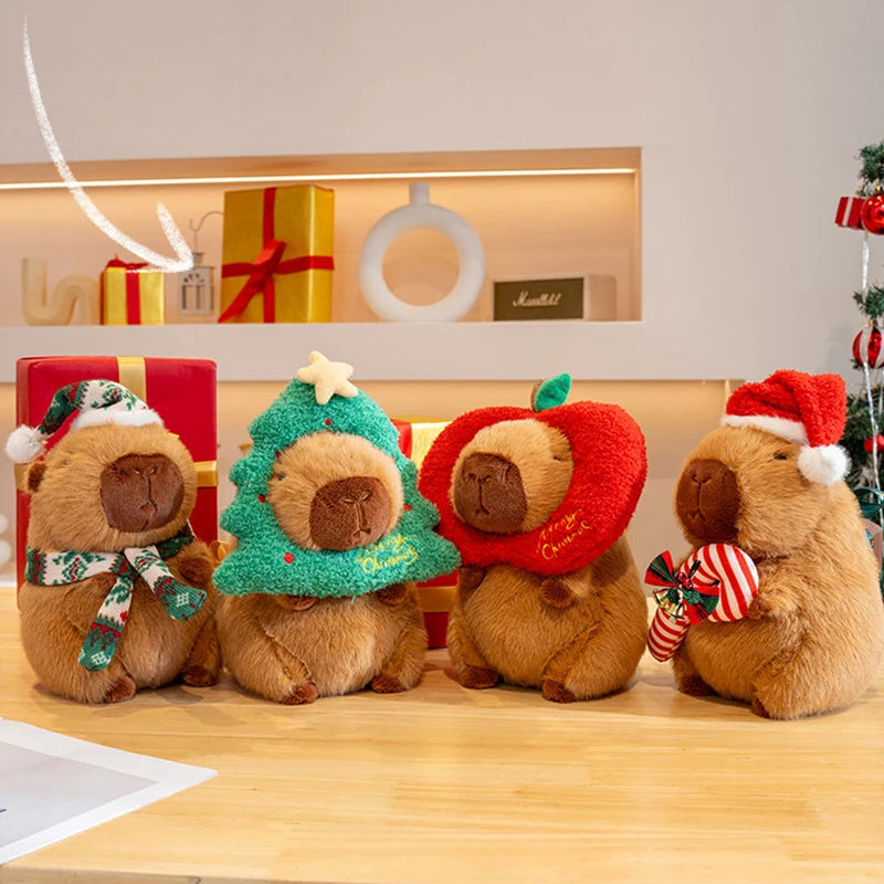 Four capybara teddy bears wearing Christmas-themed outfits on a wooden surface.