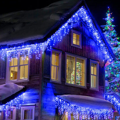 Wooden cabin decorated with blue string lights and a Christmas tree at night.