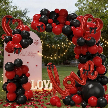Decorative arch made of red, black, and pink balloons with 'LOVE' balloons in an outdoor setting.
