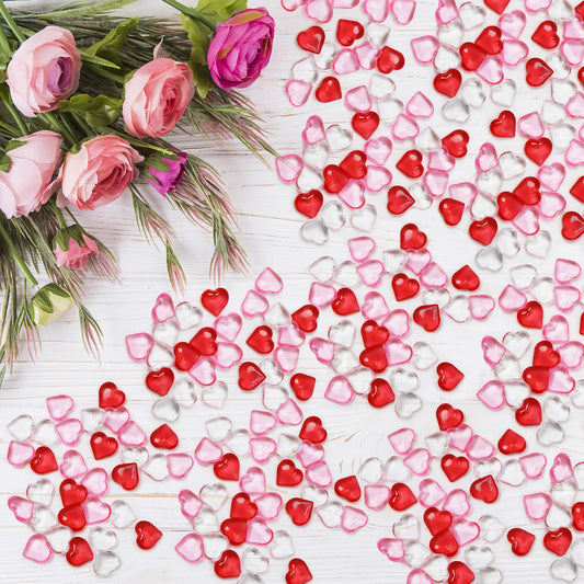 Heart-shaped confetti in red, pink, and clear on a white surface with pink roses.